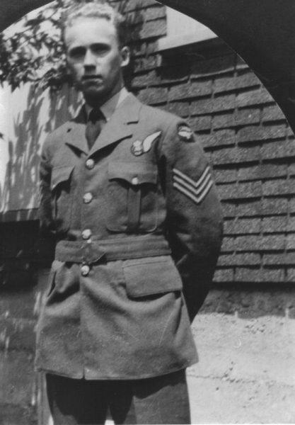 Black and white photo of a man in a military uniform standing outside.
