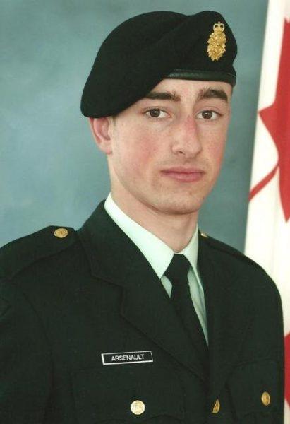 Young soldier in uniform with beret, Canadian flag in background.