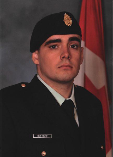 Soldier in uniform with Canada flag backdrop.