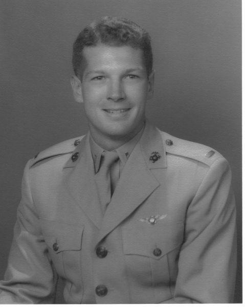 Black and white photo of a man in a military uniform, smiling.