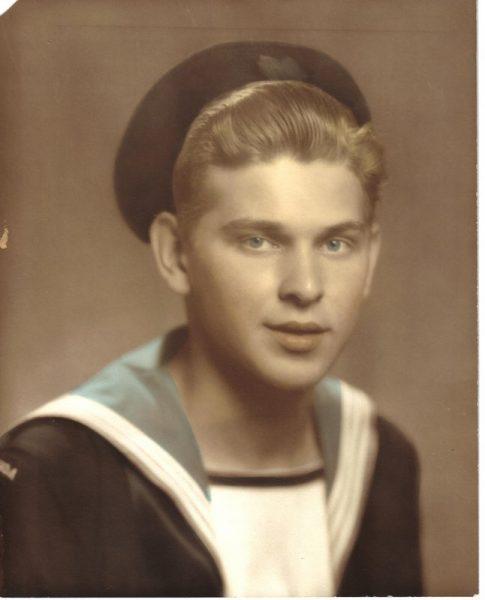 Young man in sailor uniform with a hat, sepia-toned photograph.