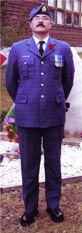 Military officer in blue uniform stands at attention outdoors.
