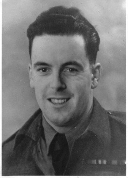 Smiling soldier in uniform, black and white photograph.