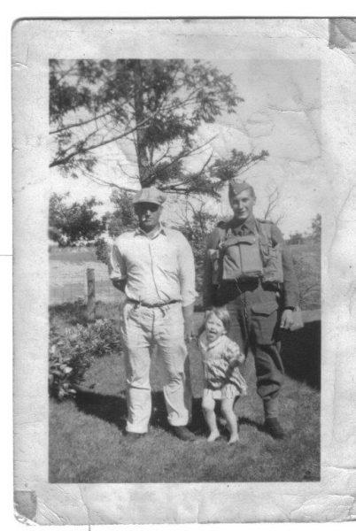 Two men and a child stand outdoors in black-and-white photograph.