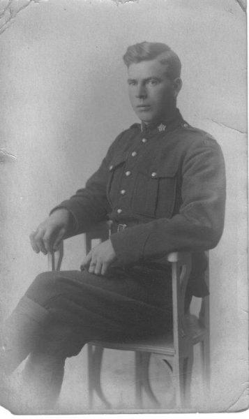 Black and white photo of a soldier seated in uniform, looking at the camera.