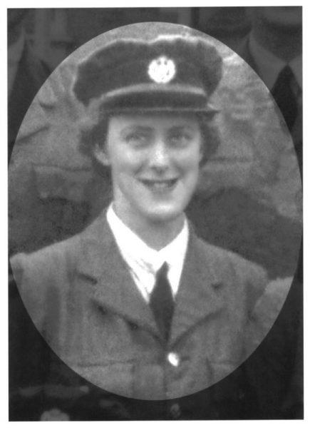 Smiling woman in vintage military uniform and hat.