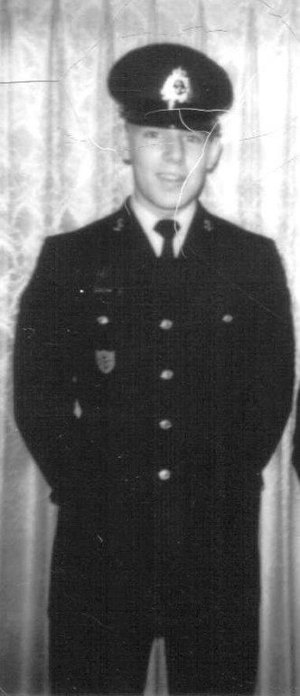 Black and white photo of a person in a military uniform, standing indoors.