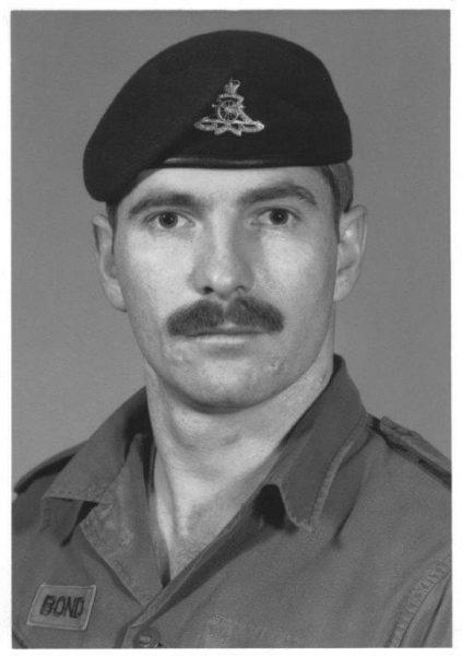 Man in military uniform wearing a beret with emblem, black-and-white photo.