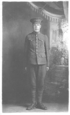 Black and white photo of a soldier in uniform, standing in a studio setting.