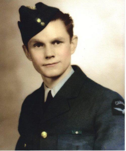 Young man in a military uniform with a cap, smiling slightly.