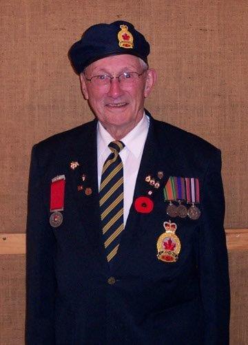 Elderly man in uniform with medals and beret, smiling.