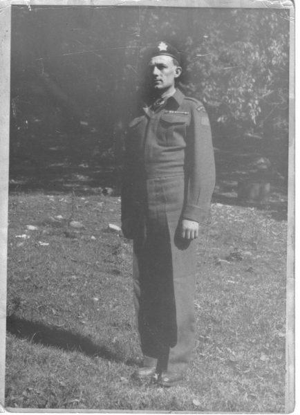 Black and white photo of a soldier standing on grass.
