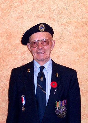 Elderly man in uniform with medals and beret, smiling.