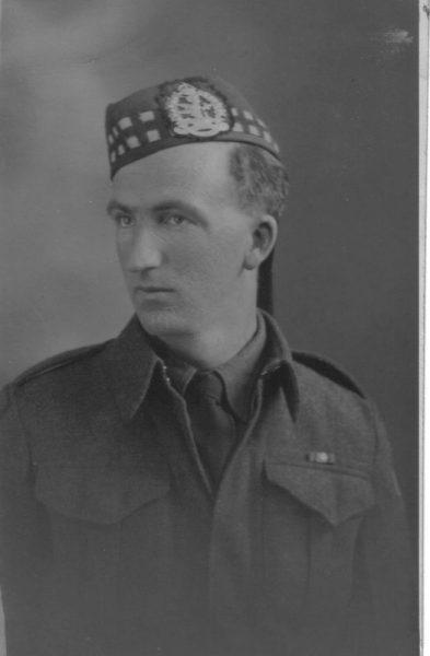 Black and white photo of a soldier in uniform with a checkered hat.