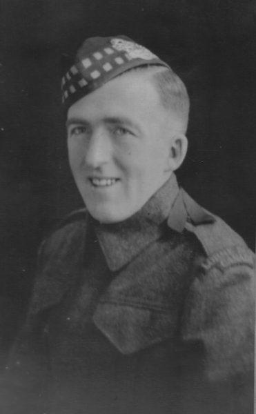 Black and white portrait of a smiling man in a military uniform with a checkered beret.
