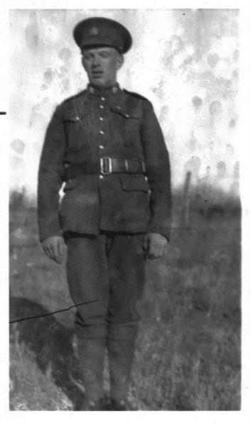 Soldier in uniform standing on grassy field, black and white photograph.