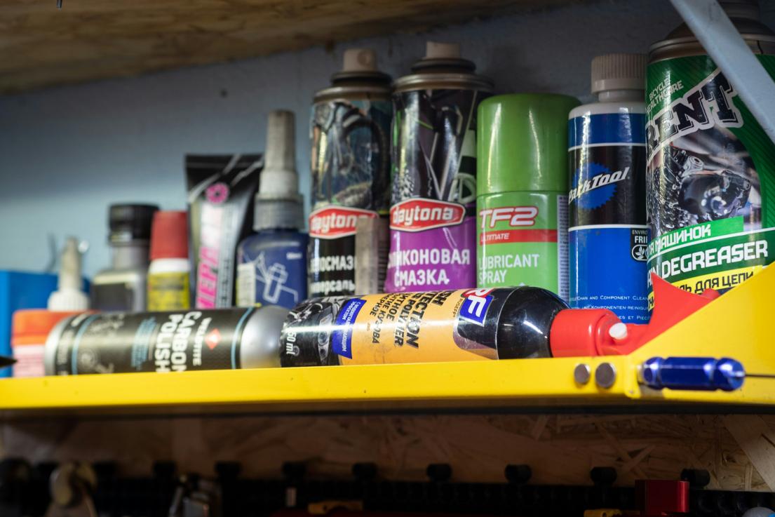 Spray paint cans and bottles of automotive products on a yellow shelf.