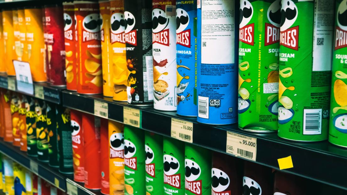 Pringles cans in various flavors on store shelves.