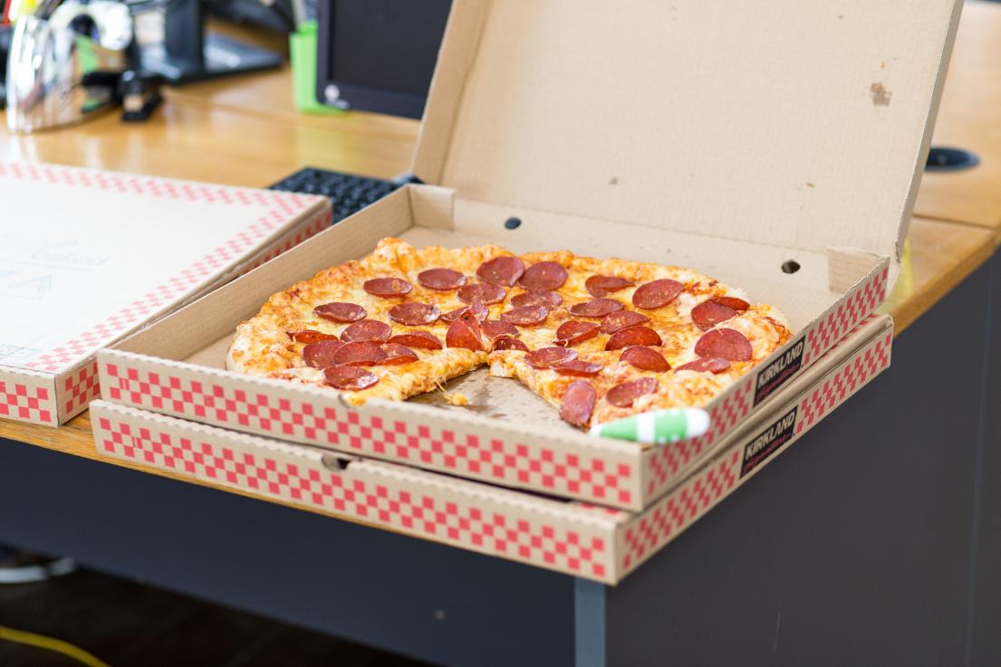 Pepperoni pizza in an open box on a wooden table.