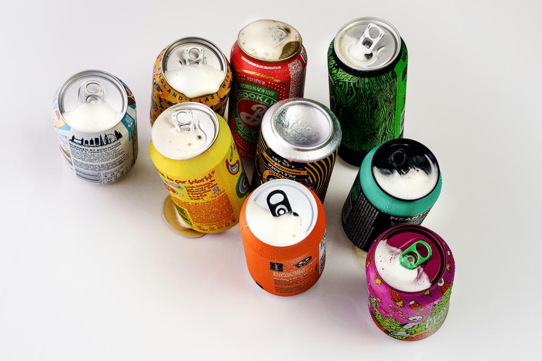 Nine colorful soda cans arranged on a white surface.