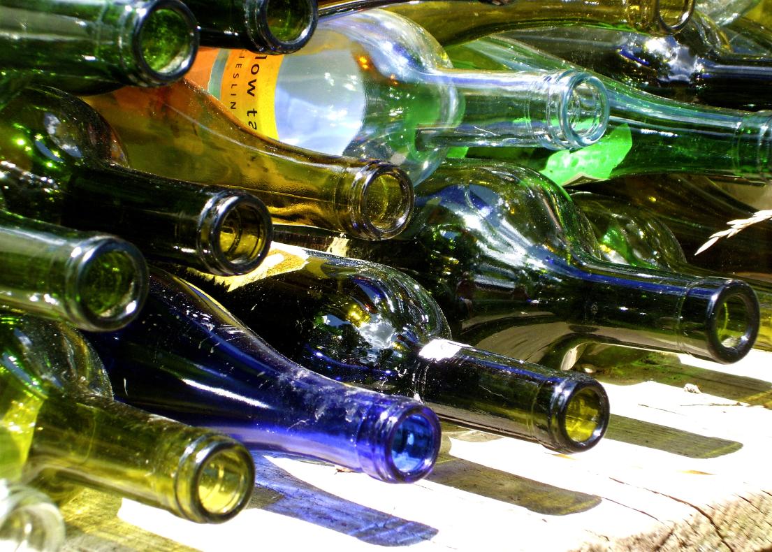 Wine bottles stacked horizontally in bright sunlight.
