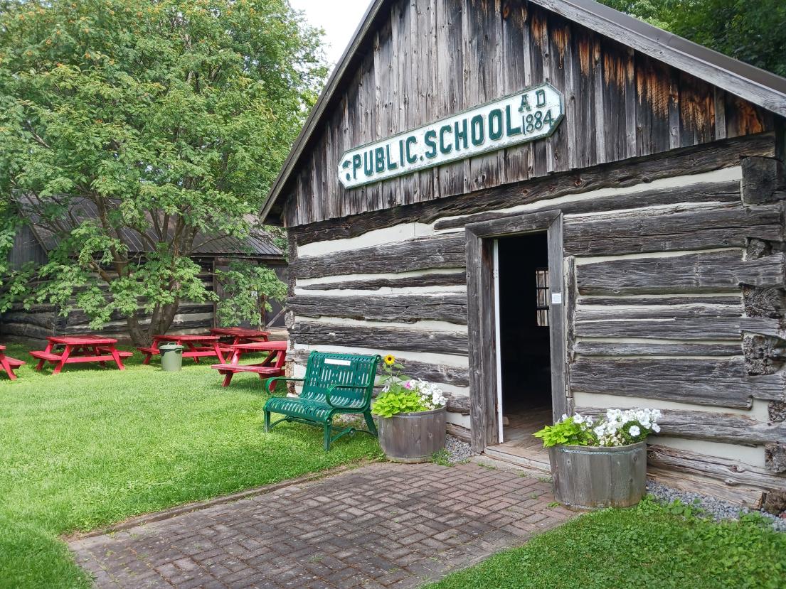outside view of a log cabin public school house. 