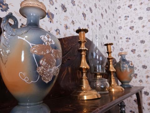 brass candlesticks and ceramics vases on a dark wood side board shelf